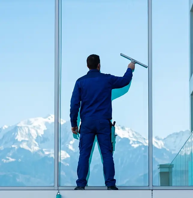 Nettoyage de vitres d’un immeuble de bureaux à Annecy, laveur vu de dos